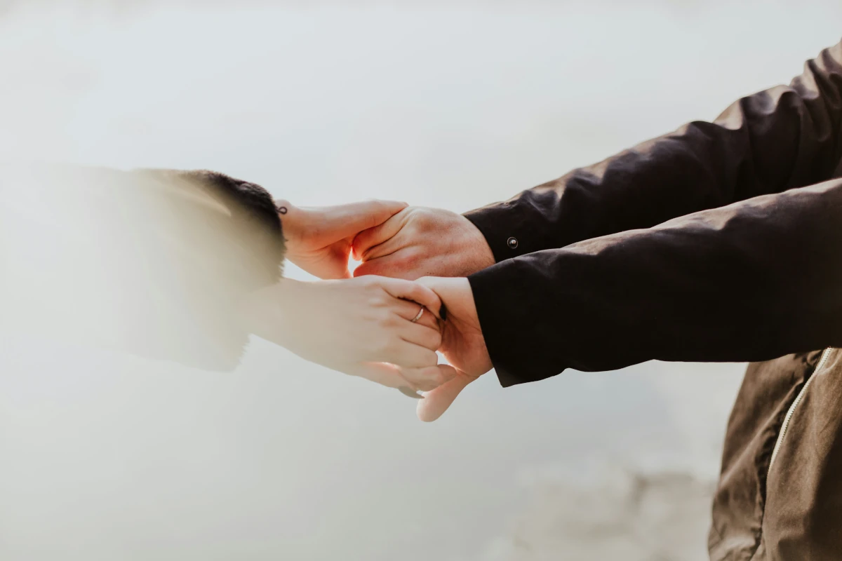 Young adult holding hands with a parent representing family support and relational healing in therapy